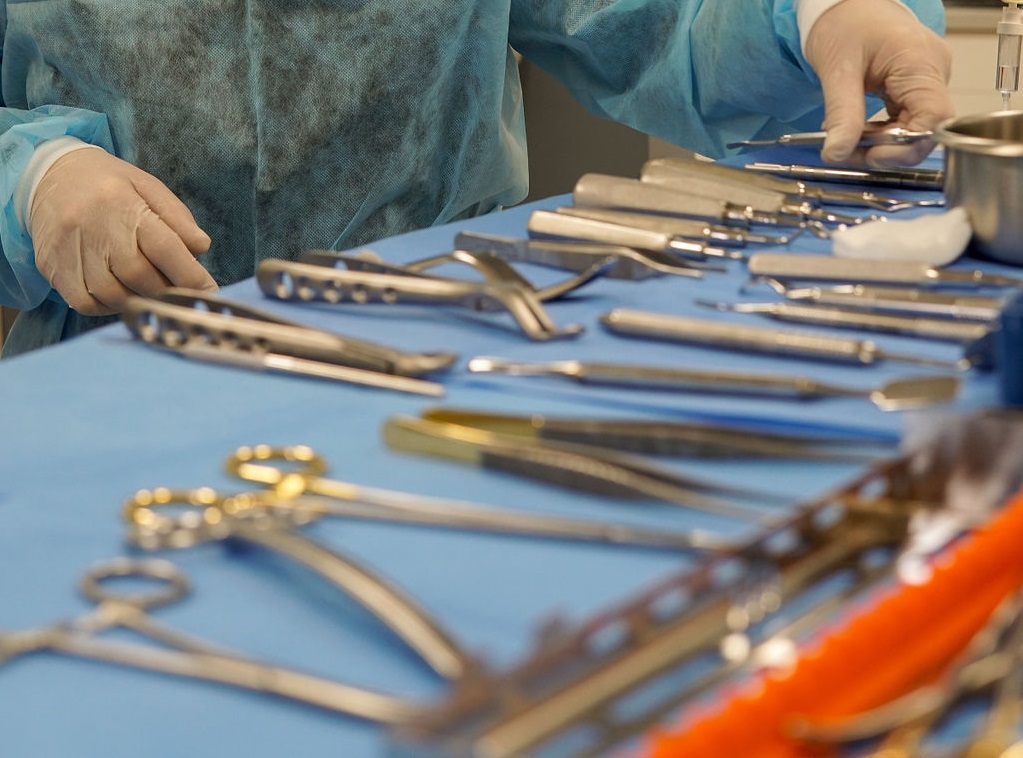 A close-up of a tray filled with various sterilized silver dental and surgical instruments arranged on a blue medical drape.