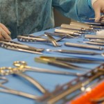 A close-up of a tray filled with various sterilized silver dental and surgical instruments arranged on a blue medical drape.